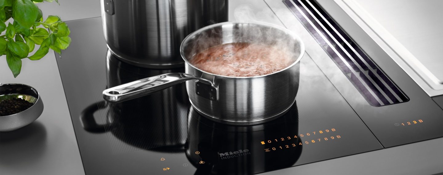 Kochtopf steht auf einem Herd mit integriertem Dunstabzug - Elektrogeräte im Küchenstudio Göbel