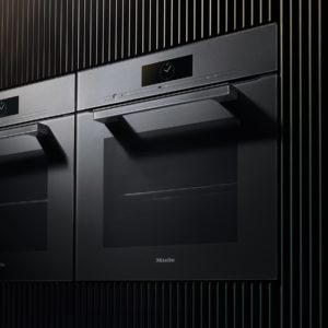 Bild zeigt ein Backofen in einer schwarzen Küchenwand - Elektrogeräte bei Sehl & Göbel