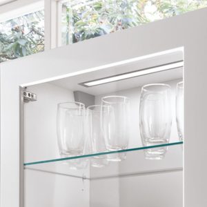 Bild zeigt eine integrierte Beleuchtung in eimen weißen Küchenschrank mit Glasfront - Elektrogeräte bei Sehl & Göbel