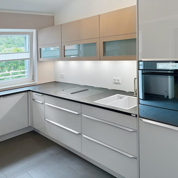 Moderne weiße Küche mit schwarzer Arbeitsfläche im Küchenstudio Göbel